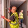 Milwaukee M18 BLPDRC-422C slagboremaskine, en kompakt og kraftfuld kulfri løsning med 145 mm længde til nem adgang i snævre områder. Billedet er et miljøbillede, hvor produktet bliver brugt i forbindelse med metal.