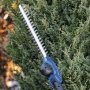 Scheppach C-PHS410-X er en kraftfuld teleskophækkeklipper. Miljø billedet viser produktet i brug