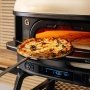 Gozney Dome Gen 2.0 Neapolitan Arch varmeforstærker. Miljøbilledet viser produktet og pizzabagning.