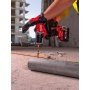 Milwaukee M18 BLPDRC-422C slagboremaskine, en kompakt og kraftfuld kulfri løsning med 145 mm længde til nem adgang i snævre områder. Billedet er et miljøbillede, hvor man kan se bygninger i baggrunden.