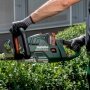 En person bruger en trådløs hækkeklipper fra Metabo, model HS 18 LTX BL 75, med et 75 cm langt sværd til at trimme en hæk.